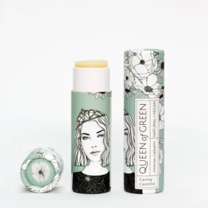 Lippenpflege in Stickform „caring Caroline“ von Queen of Green in mintfarbener, floral gestalteter Verpackung aus recyceltem Karton teilweise geöffnet mit sichtbar gelbem Balm; natürliche, vegane Lippenpflege im Stick.