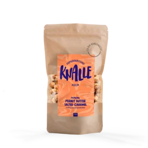 Das Bild zeigt eine Popkorn Verpackung - wiederverschließbare braune Tüte. Das Etikett ist Flamingoorange mit blauer Schrift