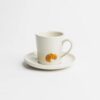 Handgefertigte Espressotasse aus Steinzeug mit glänzender Glasur in naturweiß, verziert mit einem erhabenen, handillustrierten Croissant-Motiv – jedes Stück ein individuelles Unikat.